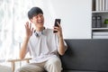 A happy young Asian man in casual clothes is looking out the window and daydreaming about his happiness while sitting on Royalty Free Stock Photo