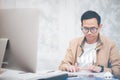 Asian man in casual clothing using a laptop communicates on the internet with the customer at  kitchen table at home. concept work Royalty Free Stock Photo