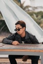an Asian man with a chubby face wearing sunglasses and a black leather jacket while sitting at a cafe table Royalty Free Stock Photo