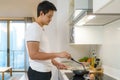 Asian man are cooking American breakfast by frying a fried egg in  pan in their kitchen at home Royalty Free Stock Photo