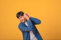 Asian man covering his ear with his hand to listen On orange background Royalty Free Stock Photo