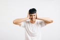 Portrait of a young man feeling stressed, covering his ears with his palms to Royalty Free Stock Photo