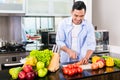 Asian man cutting salad in kitchen Royalty Free Stock Photo