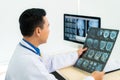 Asian man doctor holding and looking to examining x-ray of the patientÃ¢â¬â¢s skull and brain in a medical clinic at hospital Royalty Free Stock Photo