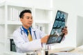 Asian man doctor holding and looking to examining x-ray of the patientÃ¢â¬â¢s skull and brain in a medical clinic at hospital Royalty Free Stock Photo