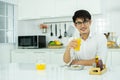 An asian man is drinking orange juice in the kitchen Royalty Free Stock Photo