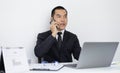 Asian man employee talking on the phone and working in a laptop with a smiling face, Office staff work and telephone conversations Royalty Free Stock Photo