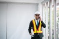 Asian man engineers using mobile phone and holding blueprint in office