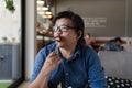 Asian man with eyeglasses eating chocolate brownie in cafe looking outside Royalty Free Stock Photo