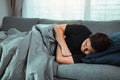 Asian man feel the illness while he was cold lying on the sofa and wearing a blanket at his house Royalty Free Stock Photo