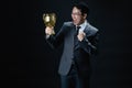 Asian man in suit happy with trophy