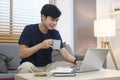 Asian man freelancer in casual clothes browsing internet, replies to email or working online via laptop computer