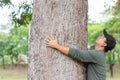 Asian man giving a hug on big mango tree. Take care the earth, Love tree and nature or environment concept