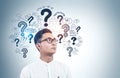 Asian man in glasses, question marks Royalty Free Stock Photo