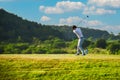 Asian man golfer standing holding and using wood driver to hitting golf ball from tee off to fairway on green grass Royalty Free Stock Photo