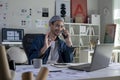 Asian man Graphic designer talking on mobile phone while working in office. Royalty Free Stock Photo