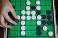 Asian man hand hold black circle of Othello Reversi on the Othello strategy board game