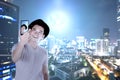 Asian man in hat making selfie using the camera phone with skyscrapers background Royalty Free Stock Photo