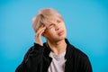 Asian man having headache, studio portrait. Korean stylish guy putting hands on head, isolated on blue background