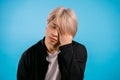 Asian man having headache, studio portrait. Korean stylish guy putting hands on head, isolated on blue background