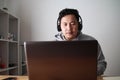 Asian man having video teleconference on his laptop at home, online learning or working from home