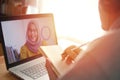 Asian man having video teleconference with a woman on his laptop at home, online learning or working from home