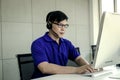 Asian man with headphones working at call center service desk consultant  talking with the customer on hands-free phone  happy Royalty Free Stock Photo