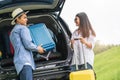 Asian man helping woman to lifting suitcase from car during travel in long weekend. Couple have road trip in vacation with yellow Royalty Free Stock Photo