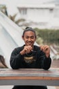 an Asian man with his hair tied up and wearing a black sweater jacket is sitting relaxing at a cafe table when meeting his friends Royalty Free Stock Photo