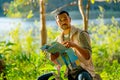 Asian man hold map and sit in the forest with relax during travel and camping in national park Royalty Free Stock Photo