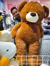 An asian man is holding a big teddy bear