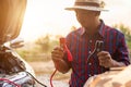 Asian man holding black and red battery cable and trying to connect the cable to his car Royalty Free Stock Photo