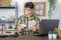 Asian man holding credit card and typing information on internet with laptop at home, online shopping concept Royalty Free Stock Photo