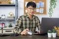 Asian man holding credit card and typing information on internet with laptop at home, online shopping concept Royalty Free Stock Photo