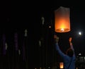 Asian man holding floating sky lanterns during Loy Kratong Festival