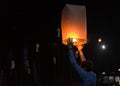 Asian man holding floating sky lanterns during Loy Kratong Festival