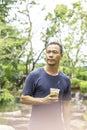 Asian man holding a glass of cold espresso coffee Background blurry views tree