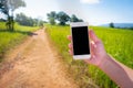 Asian man holding phone mock up black screen on the forest paths , tree , meadows , mountain and blue sky background Royalty Free Stock Photo