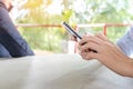 Asian man holding a phone, using smartphone while his business partner talking on a phone in background Royalty Free Stock Photo