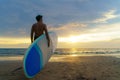 Asian man holding a sup board and paddle and walking on the beach. In the background, the ocean and the sunset. Back view. Summer Royalty Free Stock Photo