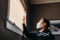 Asian man in isolation looking at medicine bottle. Man in medical mask forced to stay inside the house as a result of the