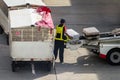 Asian man loader lifting up the luggage to conveyor belt of the trailer to loading passenger baggage to the airplane on the runway Royalty Free Stock Photo