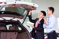 Asian man looking at car in dealership