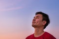 Asian man looking up to dusk sky in evening