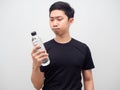 Asian man holding water bottle in his hand and feeling hesitage on white background