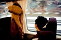 Asian man looking through window with snow. He travels on a train in Hokkaido Japan