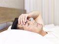 Asian man lying on bed hand on forehead