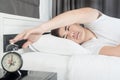 Asian man lying on the bed and stopping alarm clock Royalty Free Stock Photo