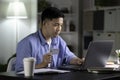 Asian man making online payment transaction using laptop and holding credit card at home Royalty Free Stock Photo