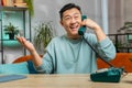 Asian man making retro telephone from 90s conversation call with friends on couch at home in room Royalty Free Stock Photo